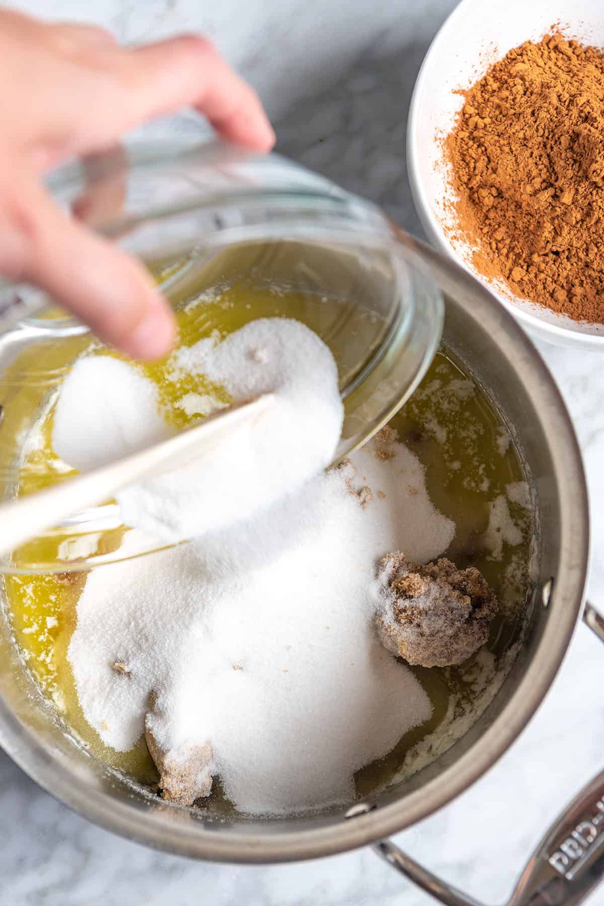 Stirring sugar into melted butter and oil for brownies.