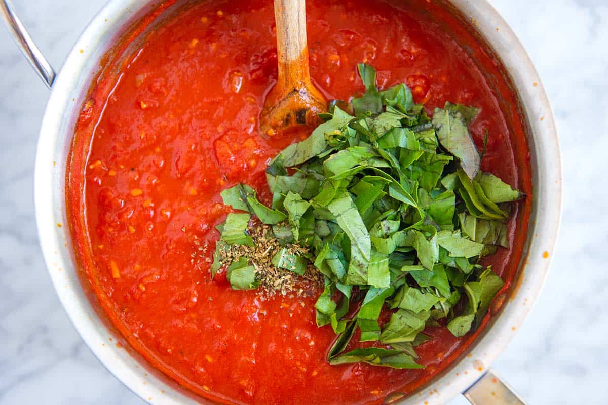 Stirring fresh basil into homemade red pasta sauce