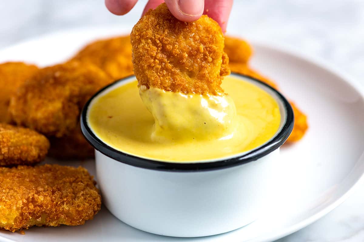 Dipping a chicken nugget into Homemade Honey Mustard Sauce