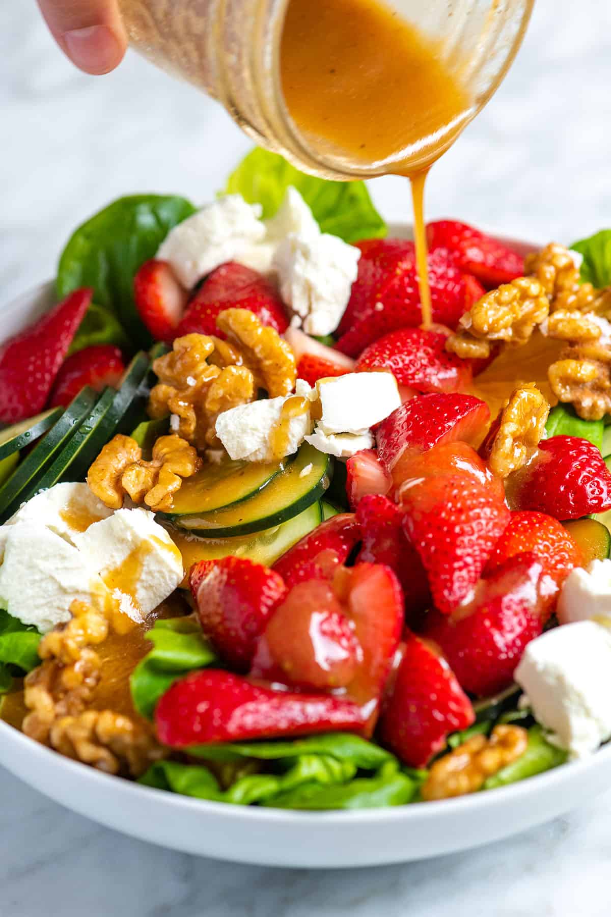 Pouring balsamic vinaigrette over our strawberry salad