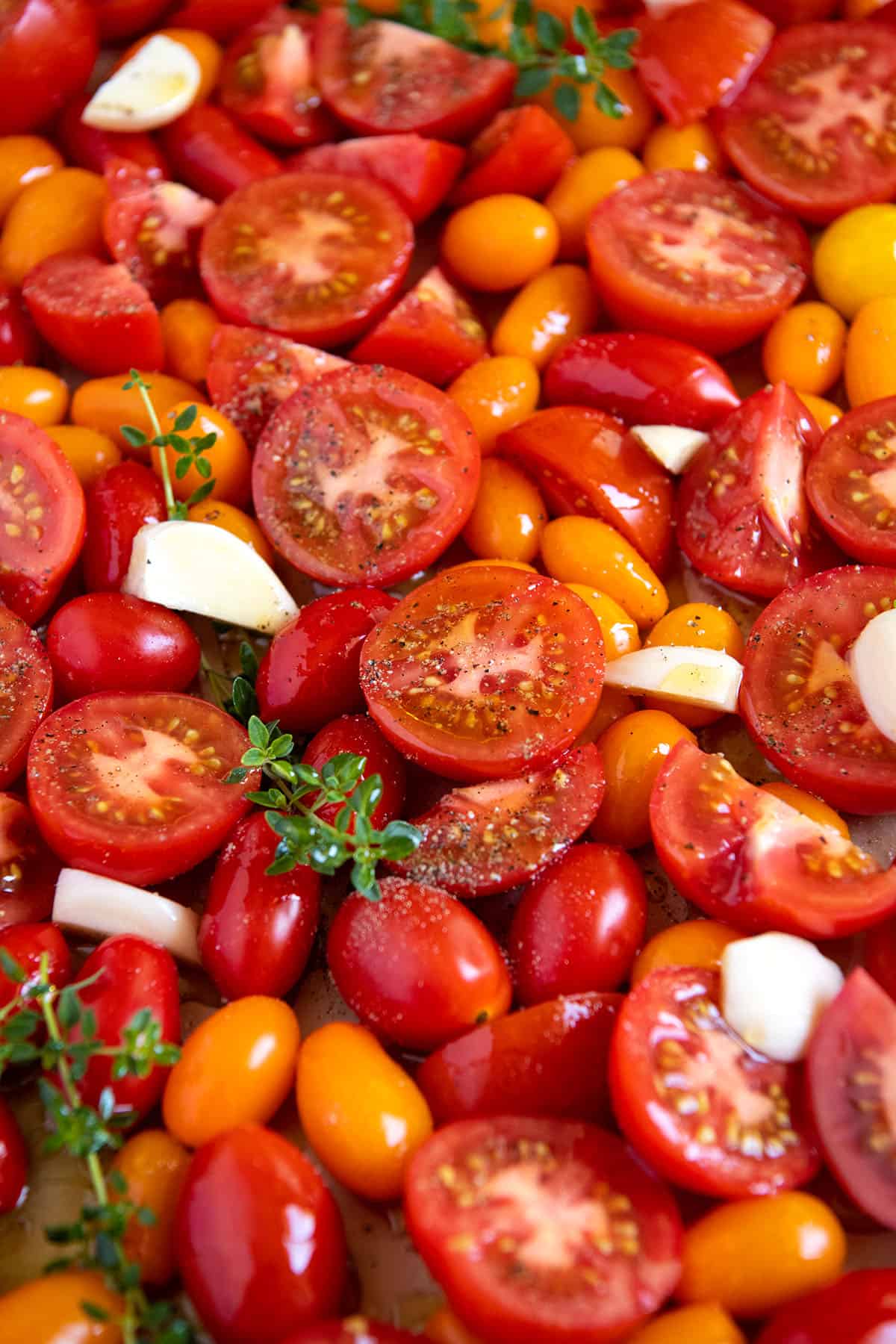 A baking sheet with tomatoes tossed with salt, pepper, and olive oil.