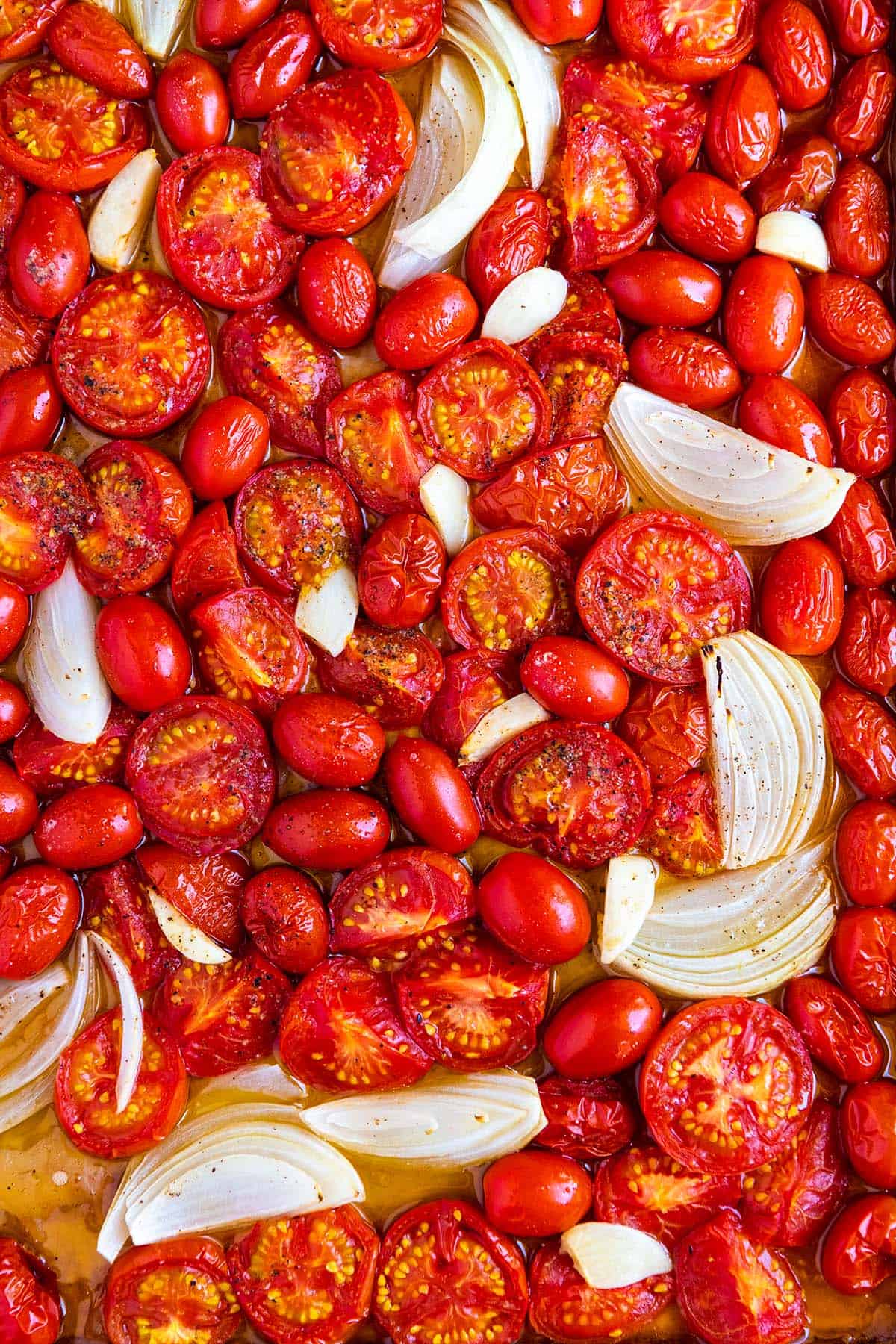 Baking sheet of roasted tomatoes, onion, and garlic ready to be turned into roasted tomato soup.