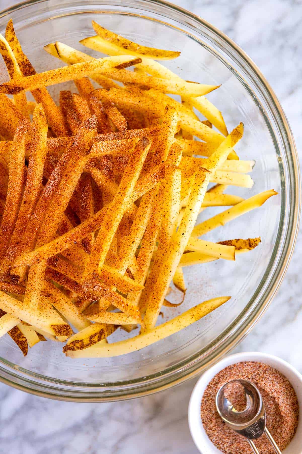 kasta skurna och blötlagda pommes frites med kryddat salt innan bakning