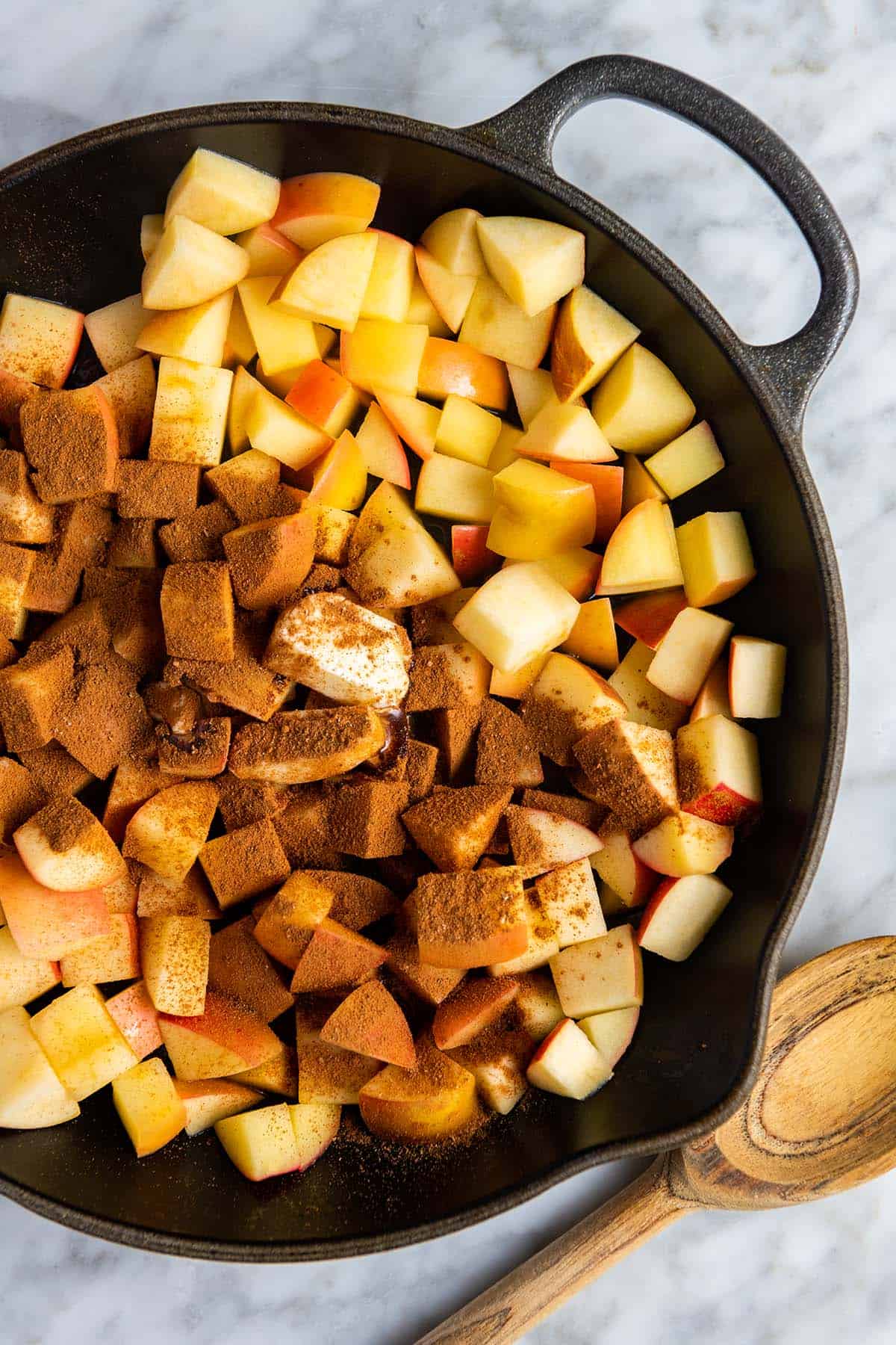 Preparare le mele alla cannella in una padella con cannella e altre spezie da forno.