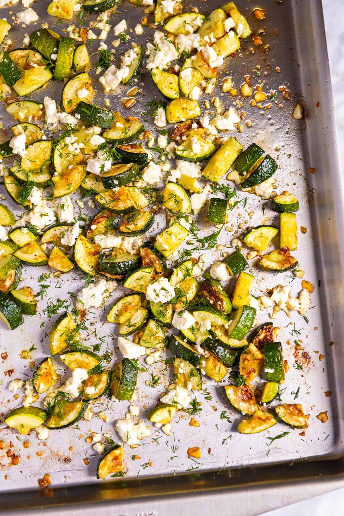 Roasted zucchini with garlic and feta on a baking sheet