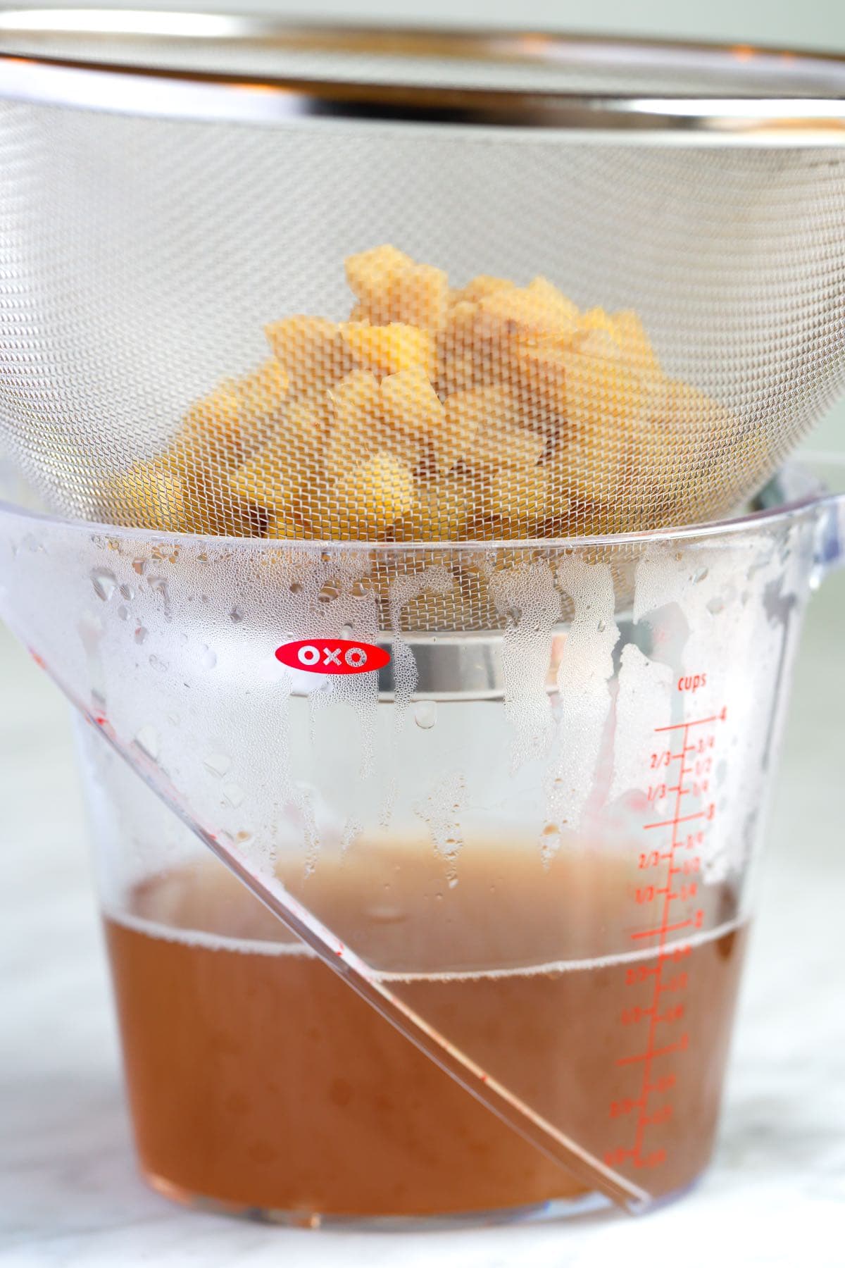 Brewed ginger tea being strained for syrup