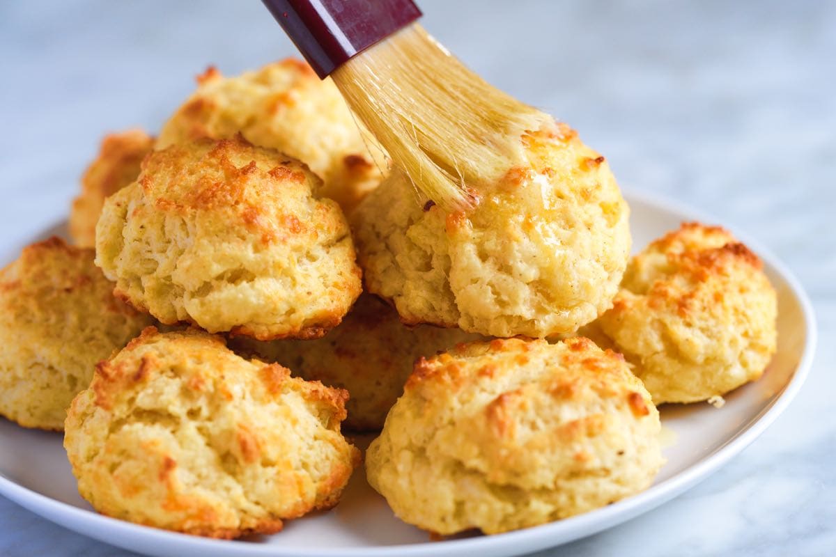 Brushing butter on top of the biscuits