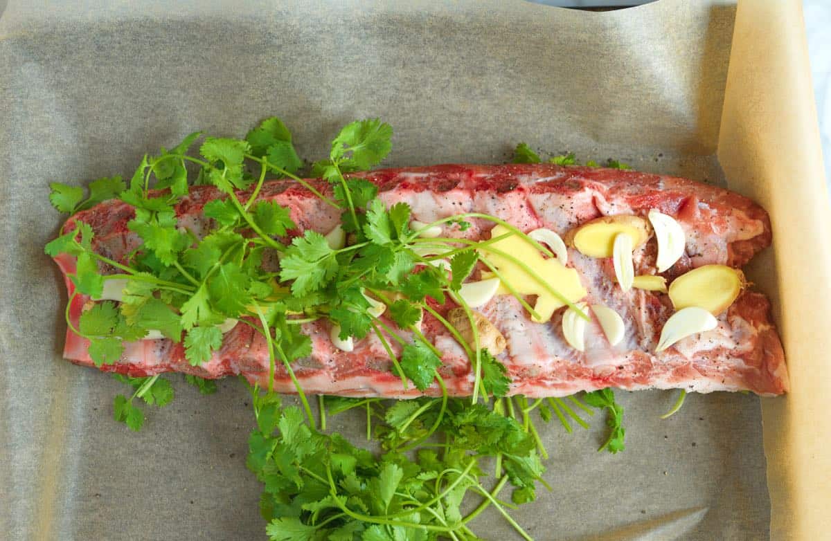 Layer ribs with sliced garlic, ginger, and cilantro.