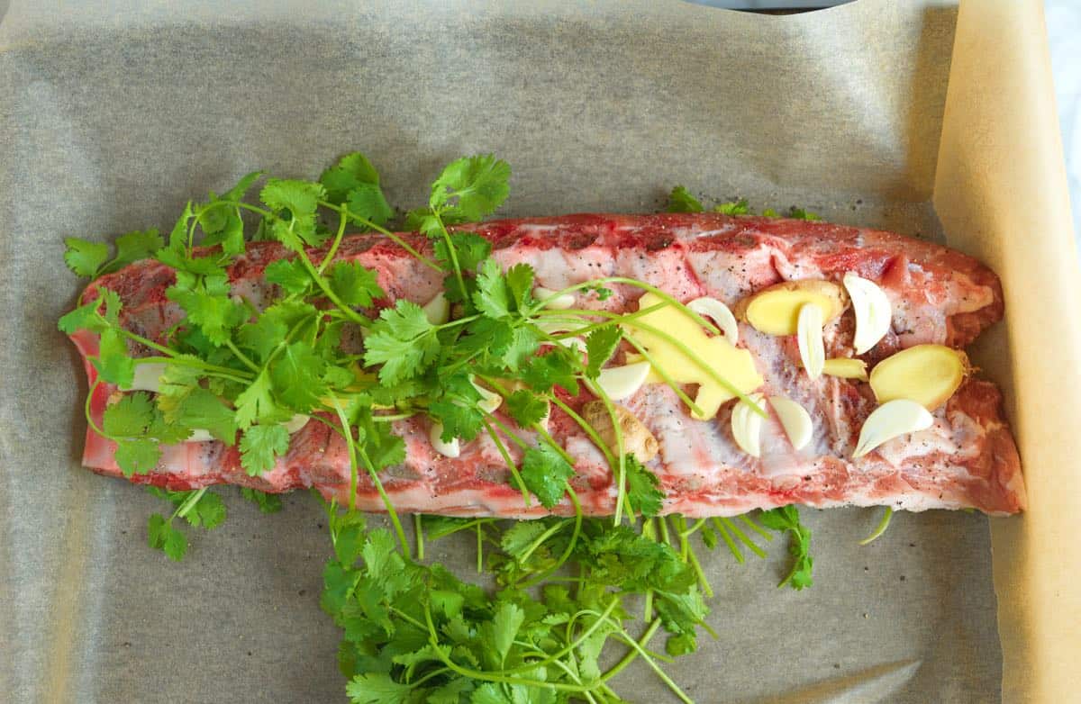 How to make Asian Ribs: Layer ribs with sliced garlic, ginger, and cilantro.