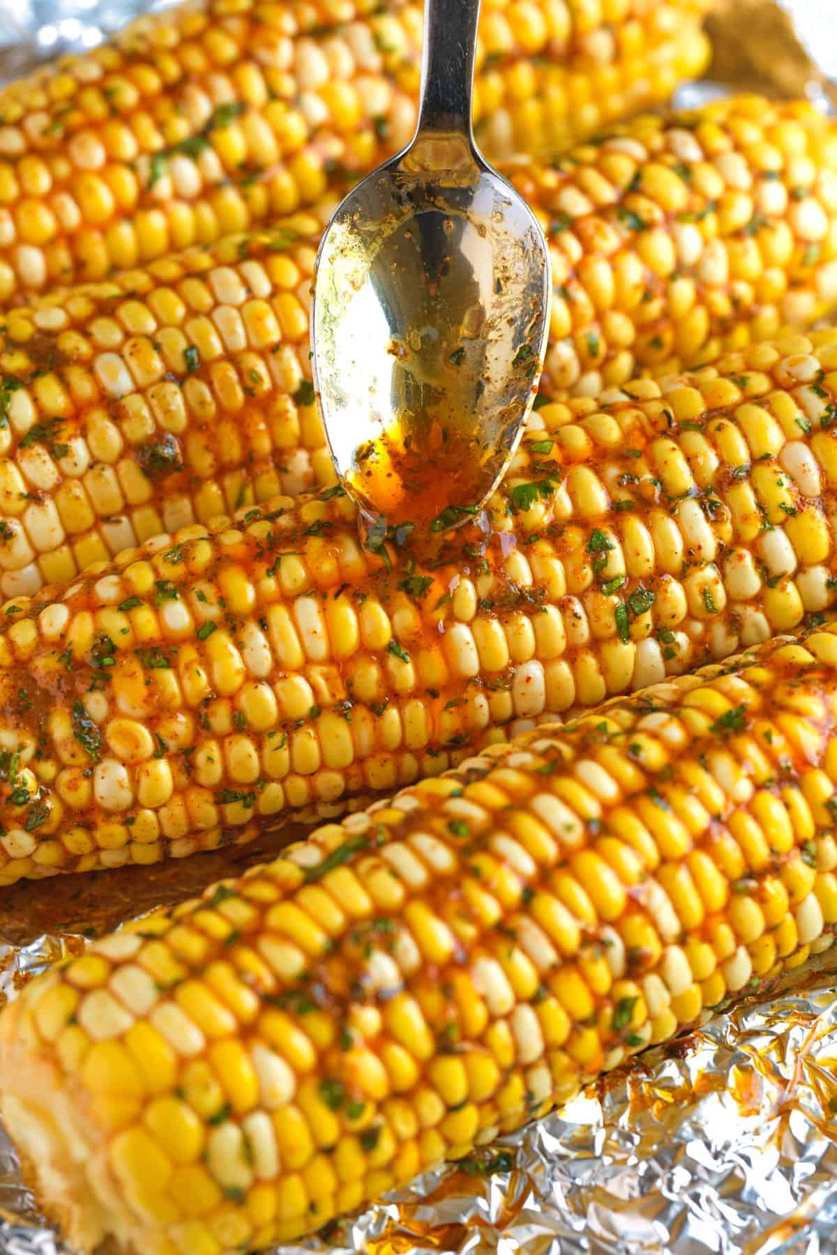 Grilled Corn with cajun butter being spooned over it