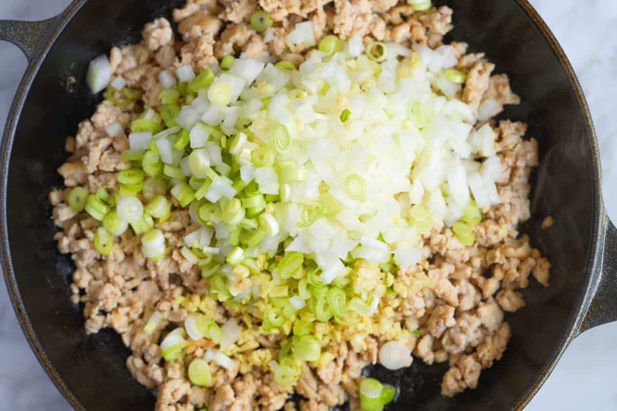 Stirring aromatics like garlic, ginger and onion into ground chicken