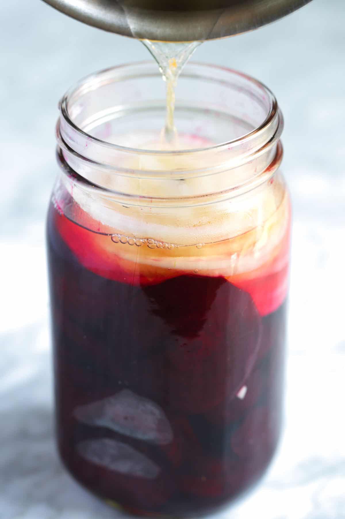 Pouring the hot brine over the beets and onions