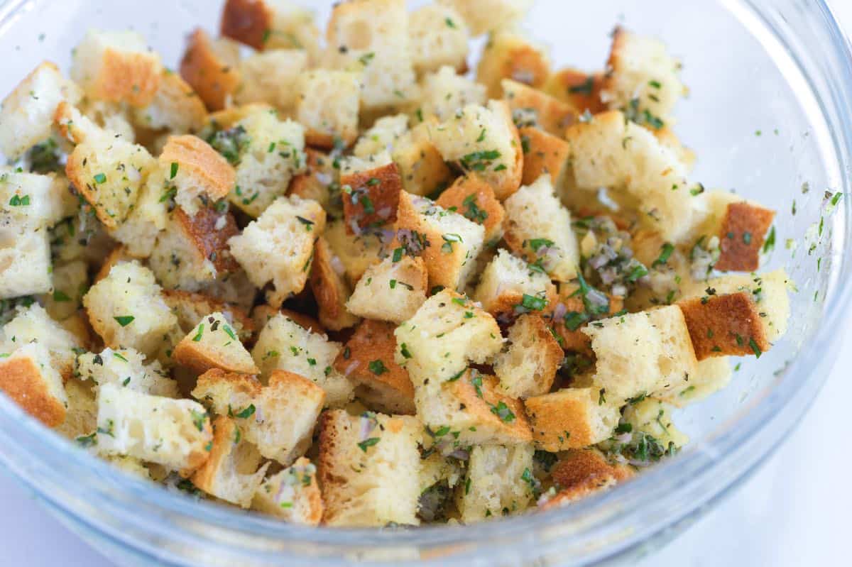 Tossing bread cubes with garlic, olive oil, and herbs