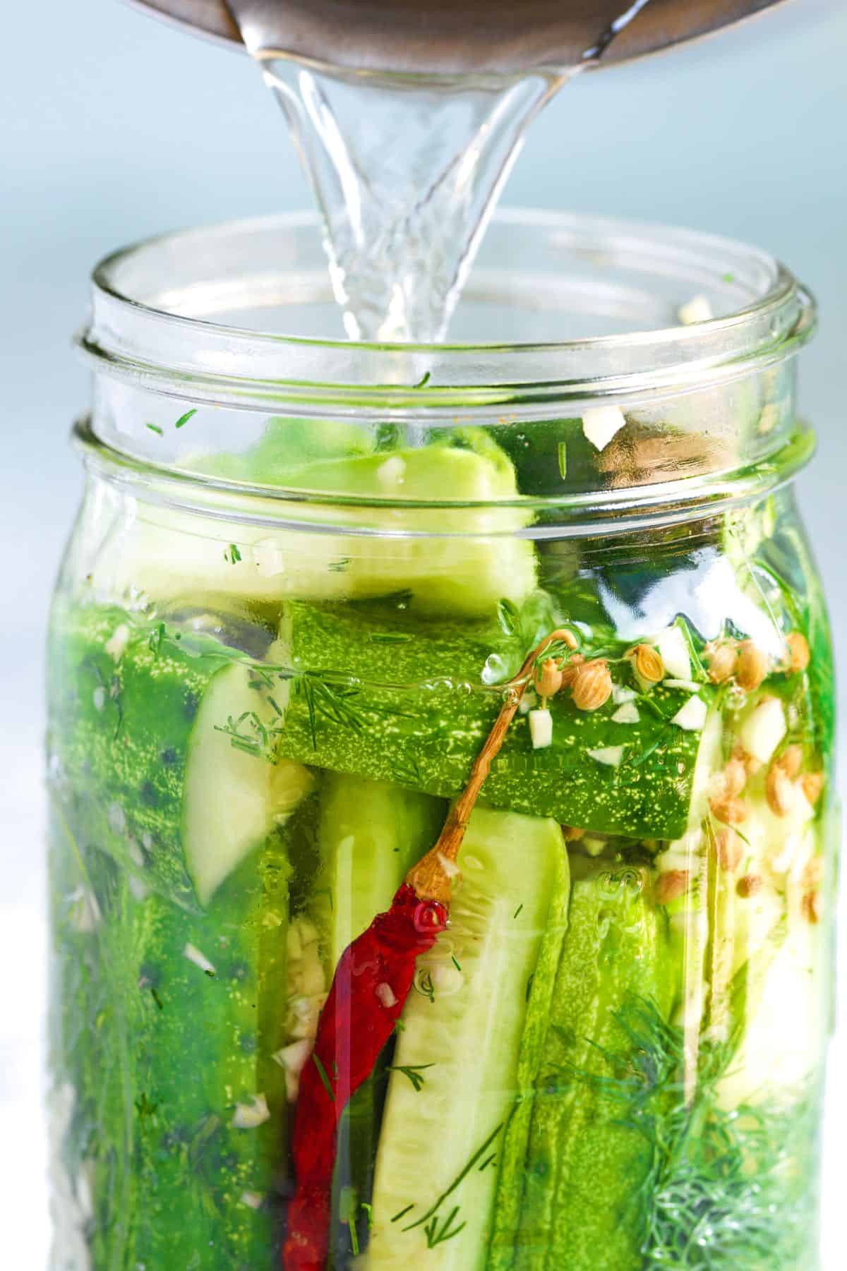 Making Homemade Pickles -- Adding brine to the jar of cucumbers