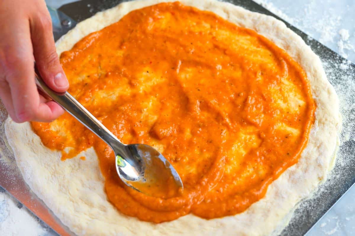 How to Make Cheese Pizza: Adding sauce to pizza crust