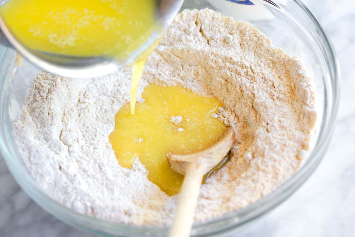 Making apple cobbler topping by pouring melted butter into flour.