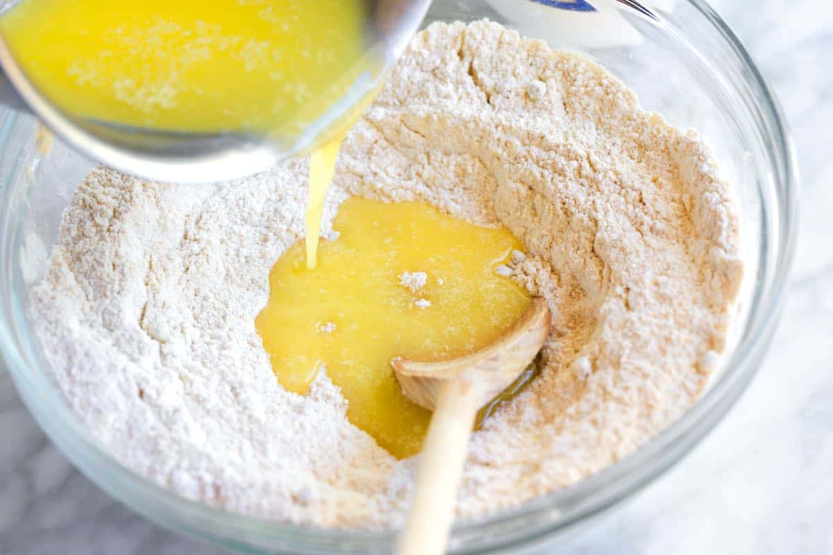 Making cobbler topping by pouring melted butter into flour.