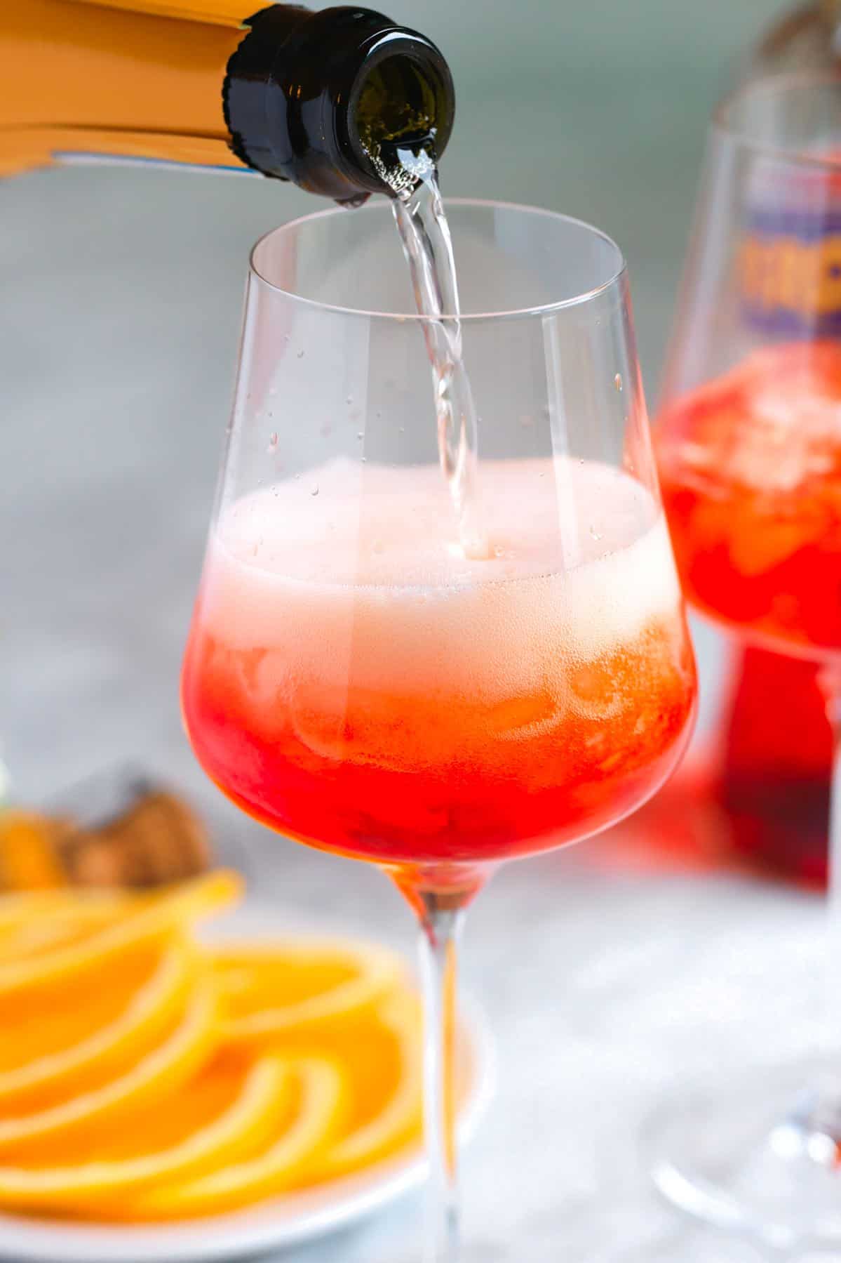 How to make an Aperol Spritz: Pouring Prosecco into a wine glass with ice and Aperol