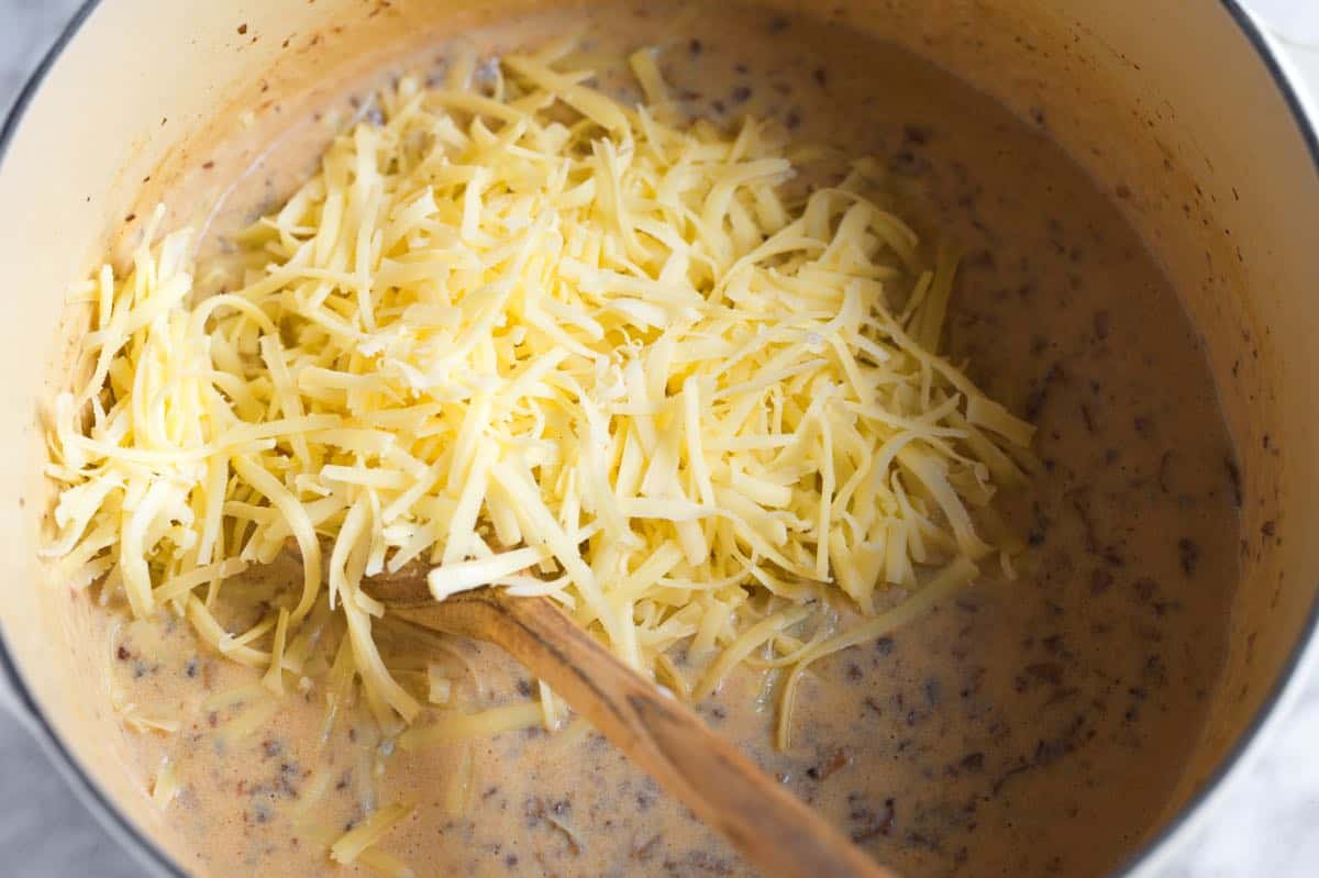 Adding cheese to our casserole sauce.