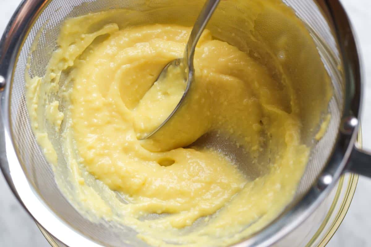 Pushing vanilla custard (for banana cream pie) through a sieve to remove lumps