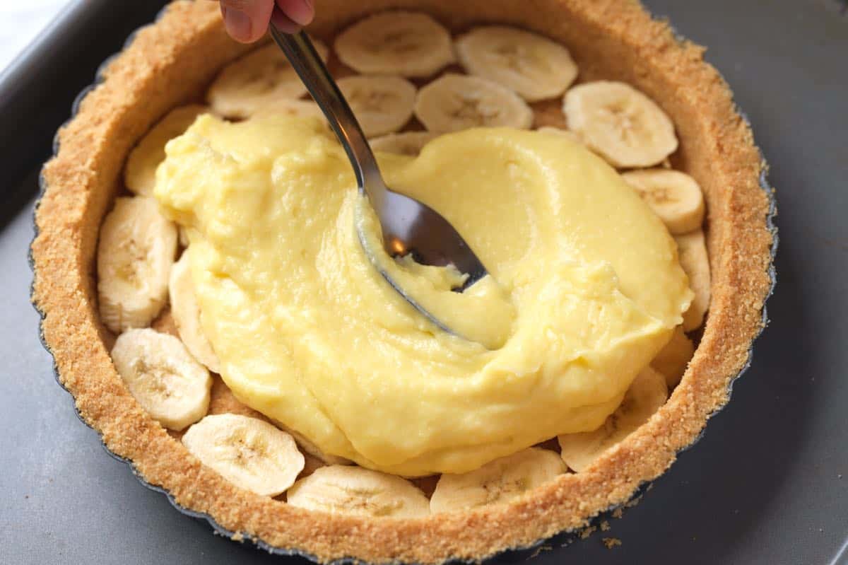 Adding vanilla custard to the crust with a layer of banana slices