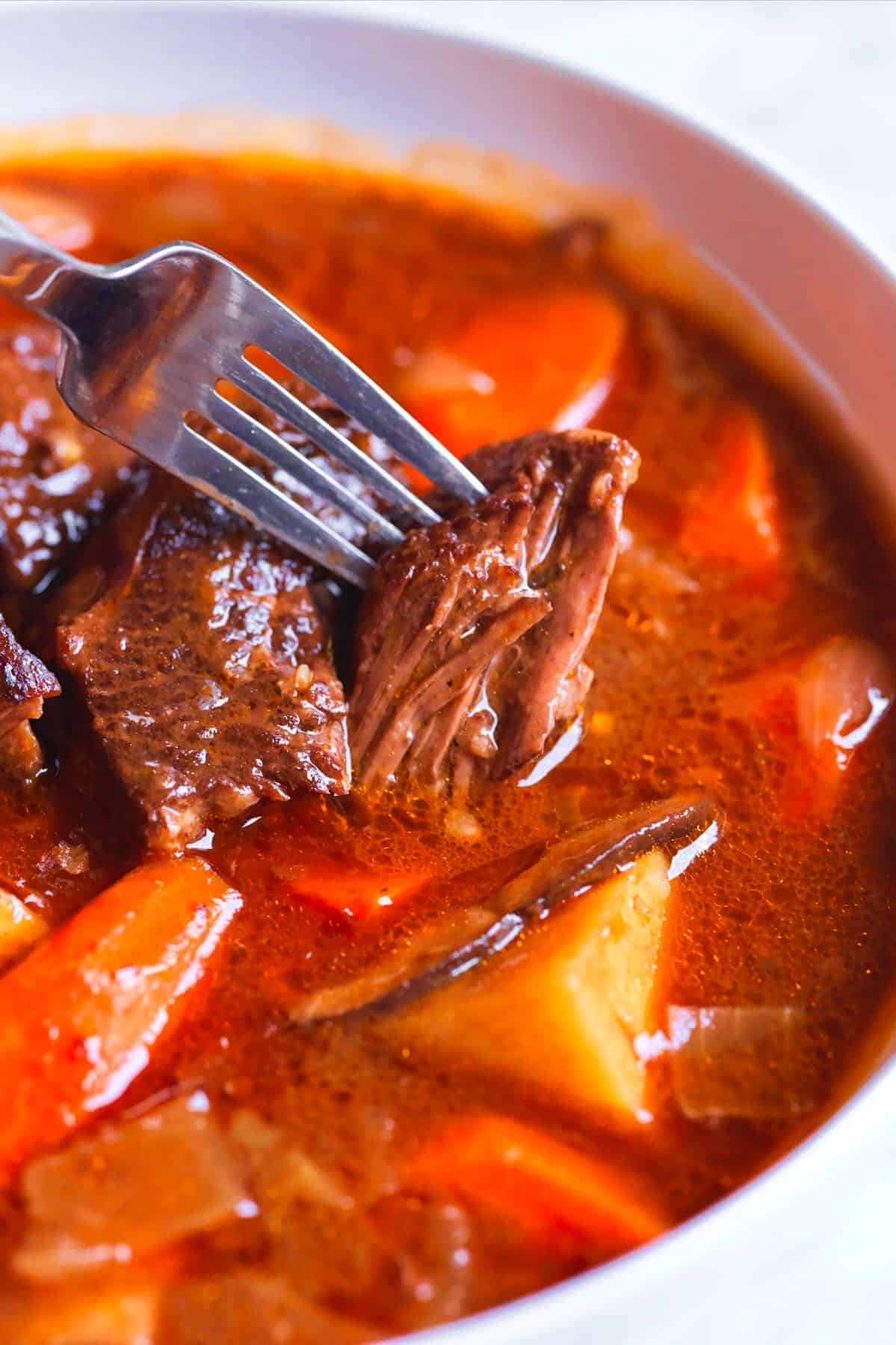 Close-up of beef stew with fork-tender meat and vegetables in a rich sauce.