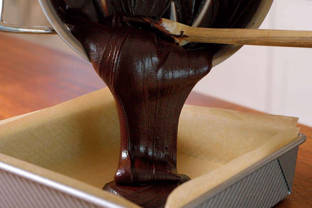 Pouring homemade brownie batter into a baking pan