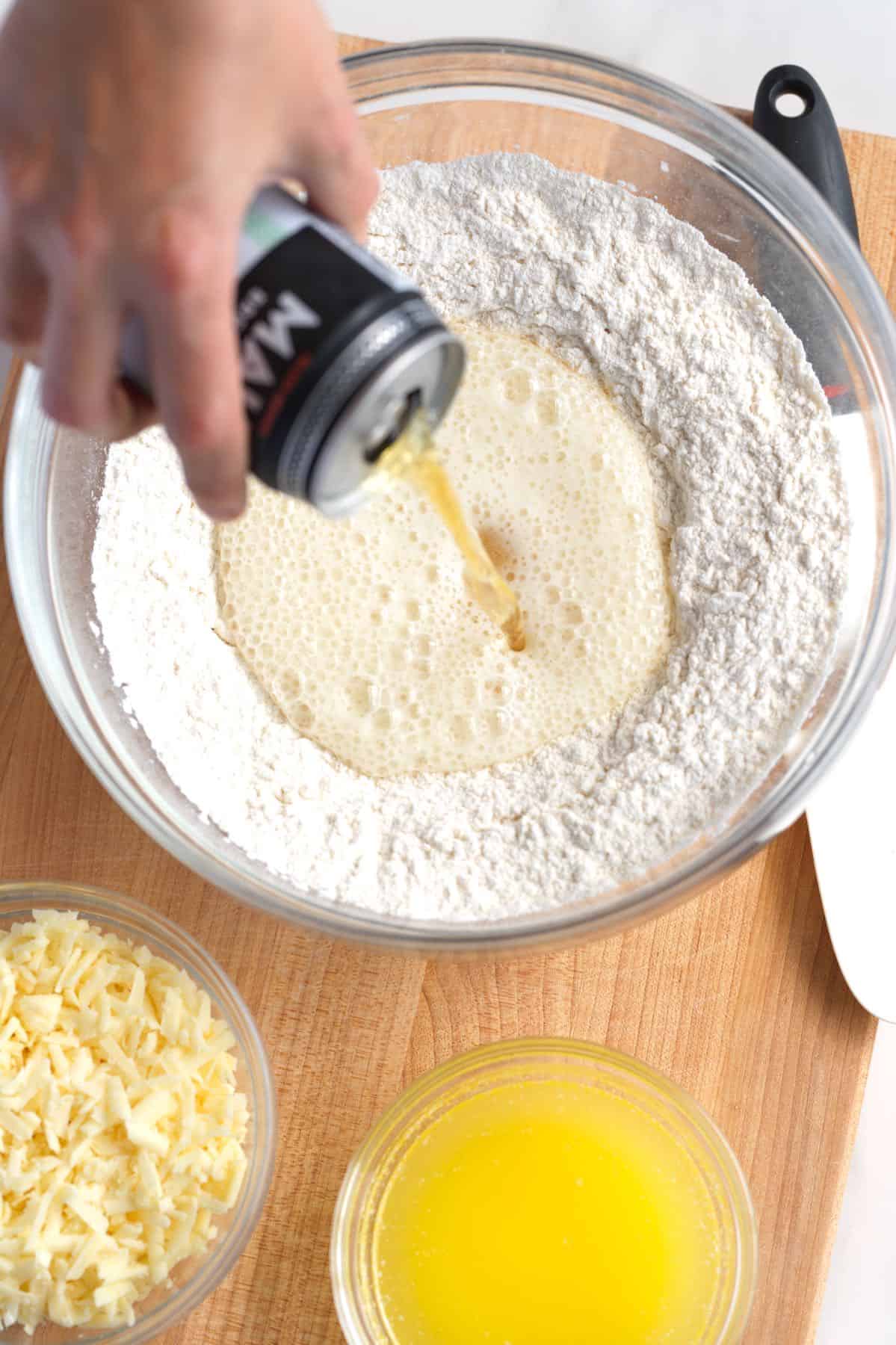 Making beer bread by pouring beer into a mixture of flour, sugar, and salt.