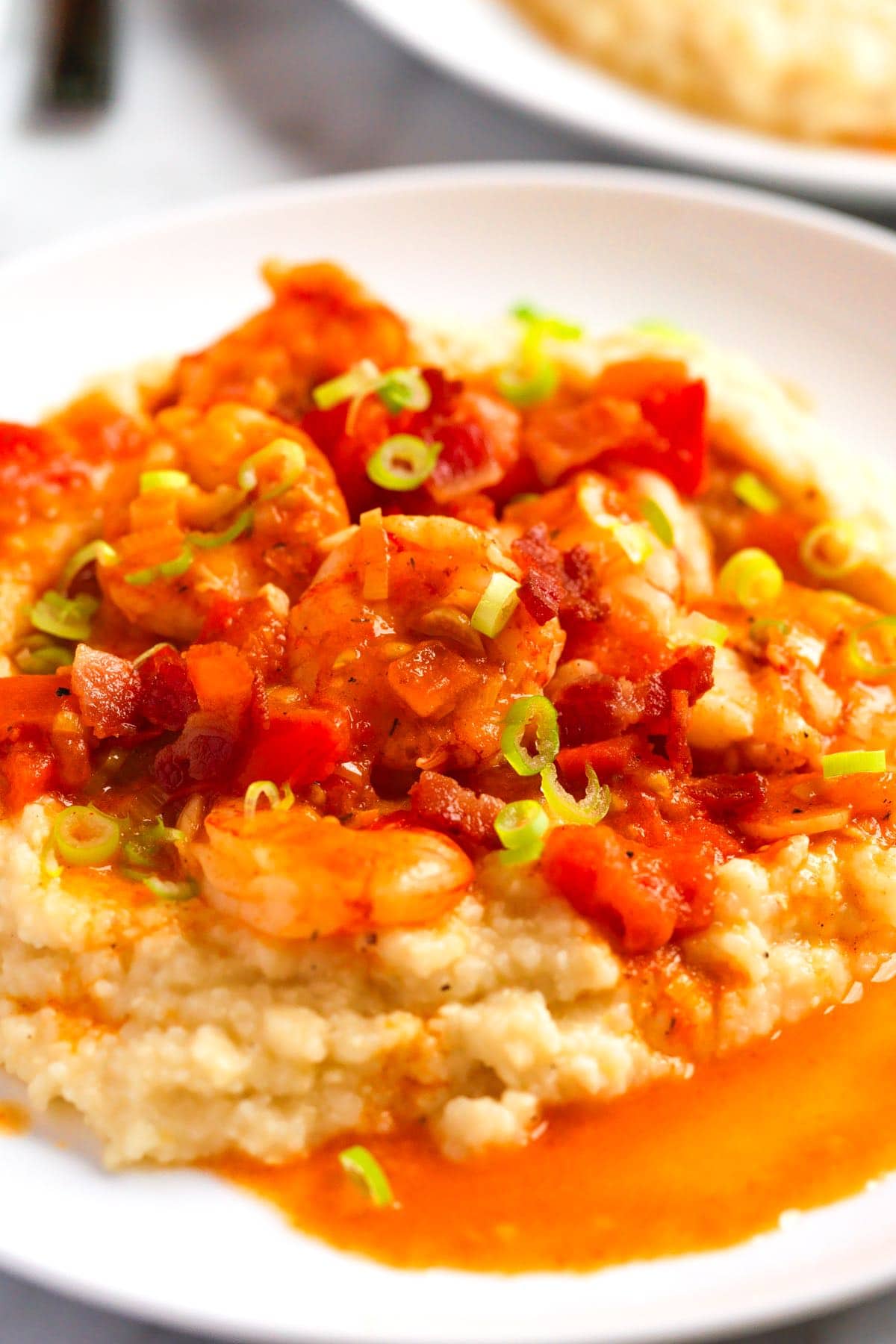 Delicious shrimp and grits with a sauce made with fresh tomatoes, Creole (or Cajun) seasoning, and bacon.