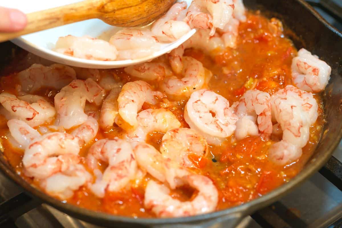 Adding the shrimp to the shrimp and grits sauce.