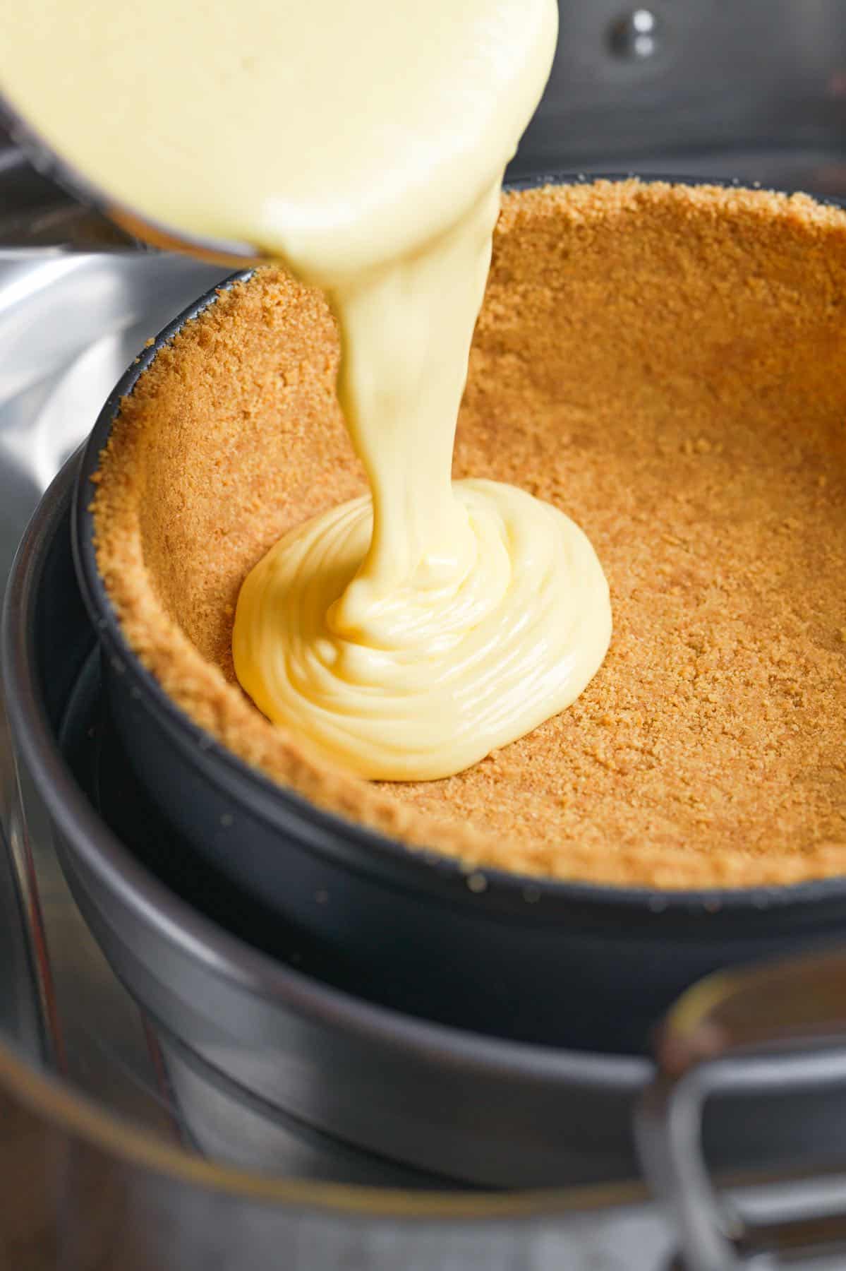 Pouring cheesecake filling into a graham cracker crust