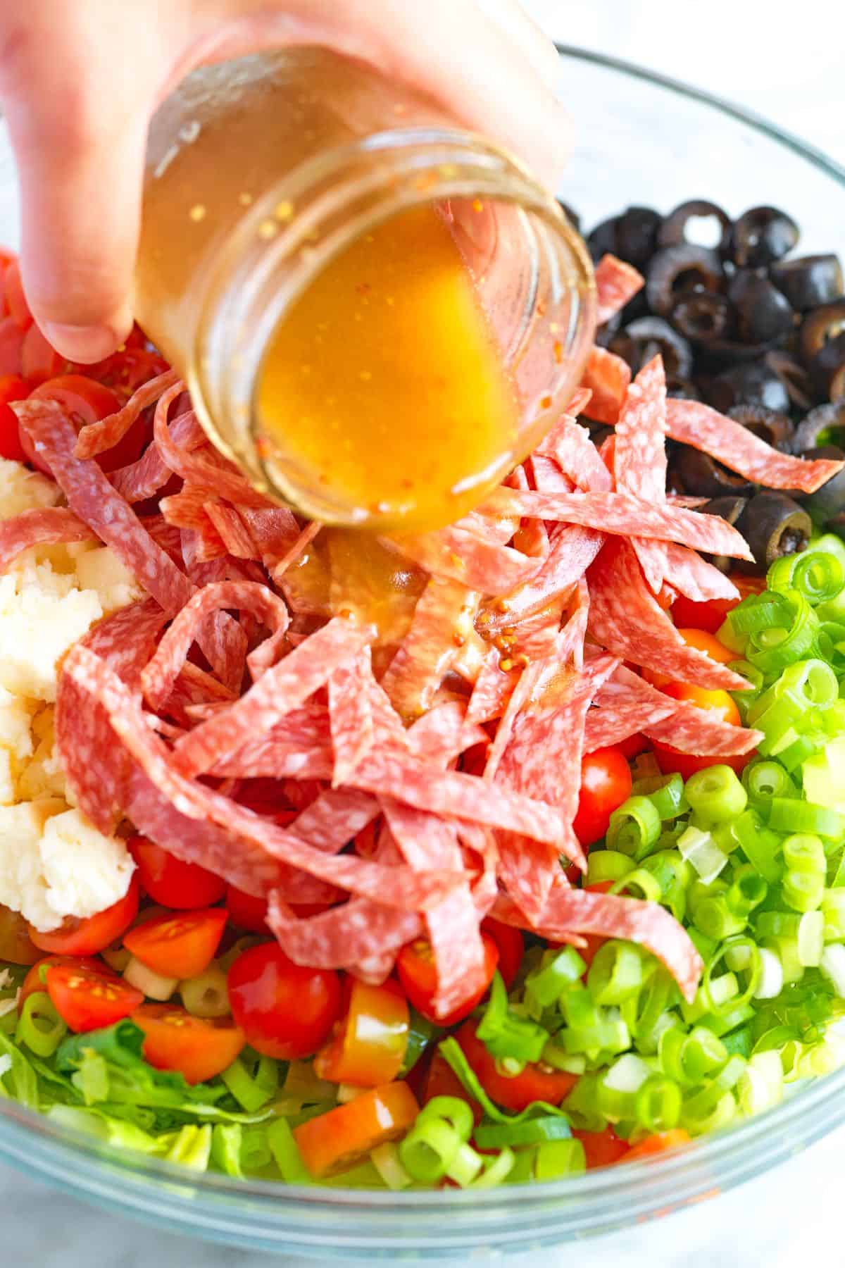 Pouring the red wine vinegar salad dressing over our chopped Italian salad.
