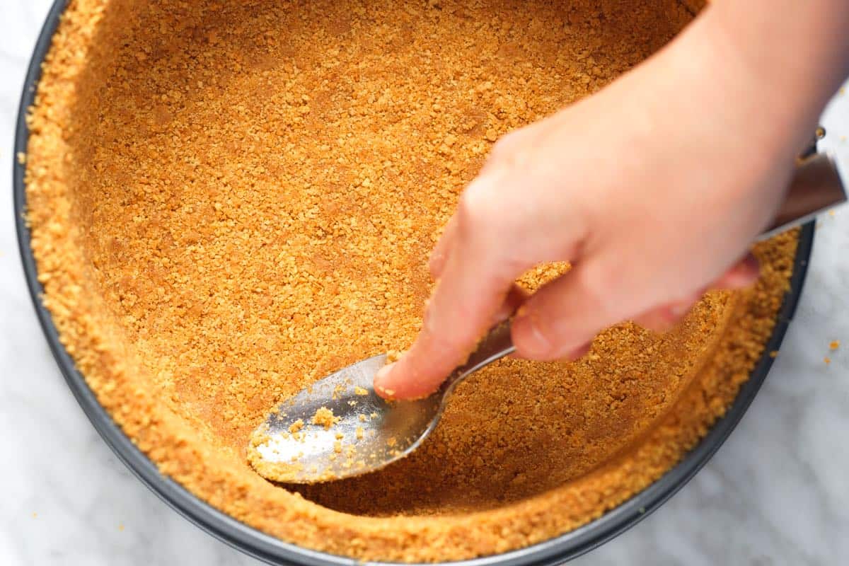 Smoothing edges of a graham cracker crust before adding cheesecake filling