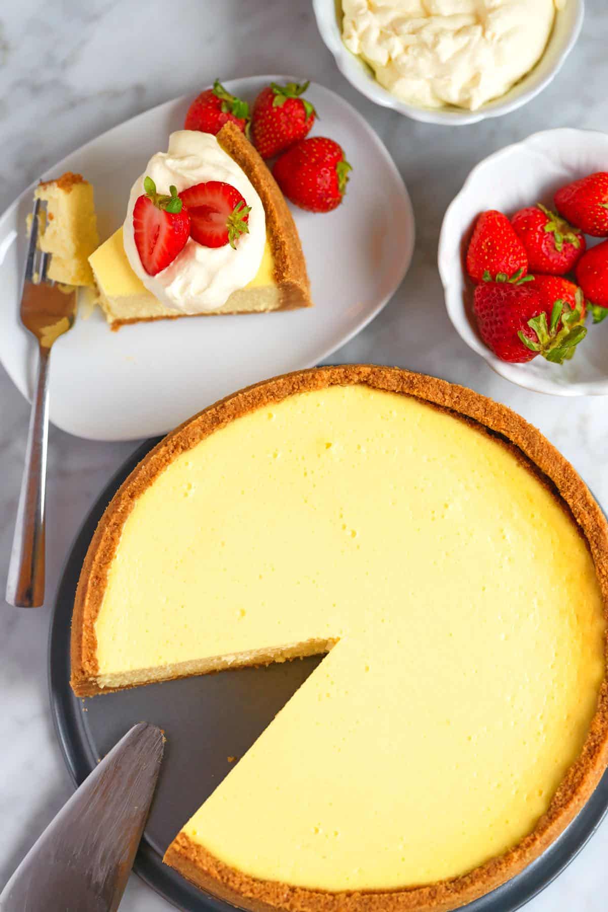 Baked and cooled New York cheesecake with whipped cream and strawberries