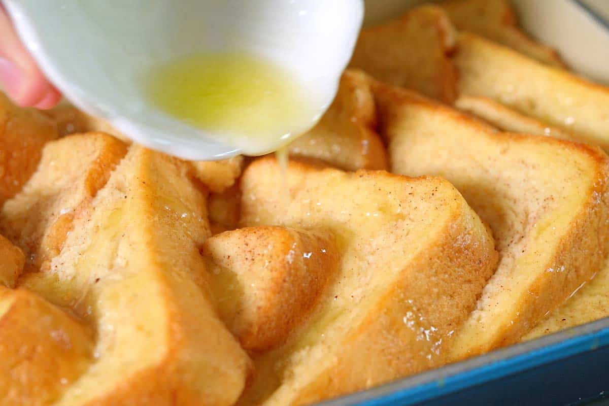 How to make baked French toast - pouring butter and adding cinnamon sugar to the top