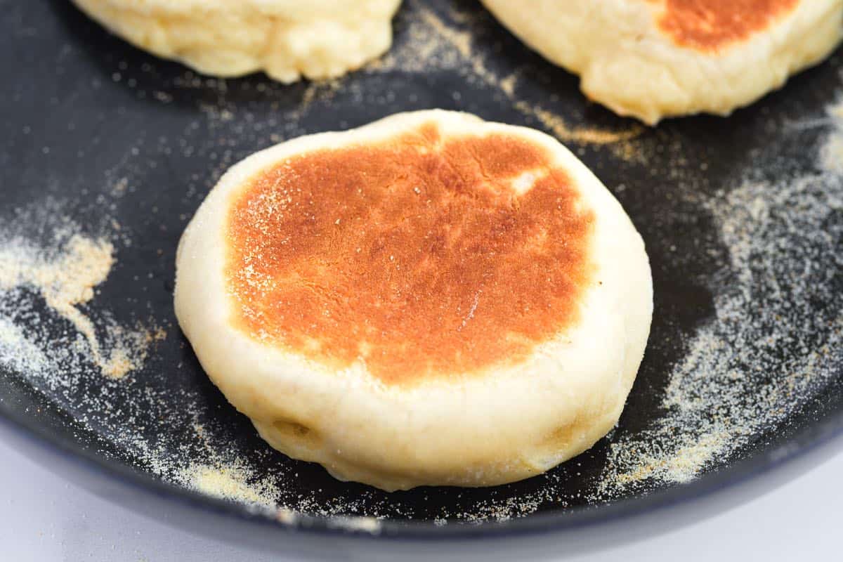 Cooking Homemade English Muffins in a skillet with semolina flour